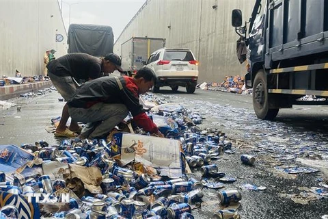 Nhiều người dân hỗ trợ tài xế dọn dẹp các vỏ lon bia bị đổ ở hầm chui ngã tư Vũng Tàu (Biên Hòa, Đồng Nai). (Ảnh: Lê Xuân/TTXVN)