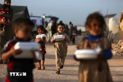Trẻ em Syria nhận thức ăn cứu trợ tại trại tị nạn ở Dana, tỉnh Idlib. (Ảnh: AFP/TTXVN)