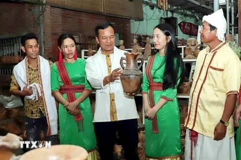 Ông Đàng Chí Quyết giới thiệu với du khách về gốm truyền thống của làng nghề. (Ảnh: TTXVN phát)
