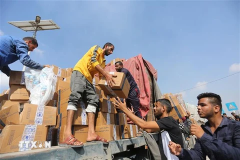 Bốc dỡ hàng viện trợ cho người dân Gaza tại khu vực cửa khẩu Rafah. (Ảnh: THX/TTXVN)