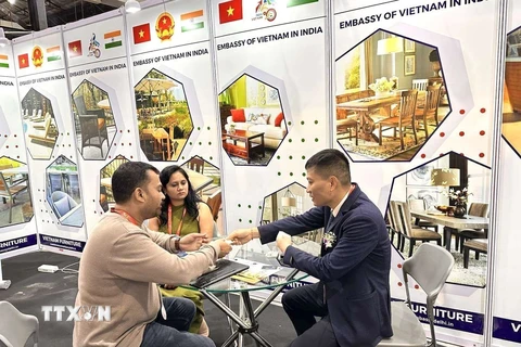 Đại diện Thương vụ Việt Nam tại Ấn Độ trao đổi thông tin với khách tham quan Triển lãm Đồ gỗ Nội thất Quốc tế tại gian trưng bày sản phẩm của Việt nam. (Ảnh: Ngọc Thúy/TTXVN)