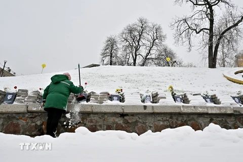 Người dân thu dọn tuyết tại một nghĩa trang ở Kiev, Ukraine. (Ảnh: AFP/TTXVN)