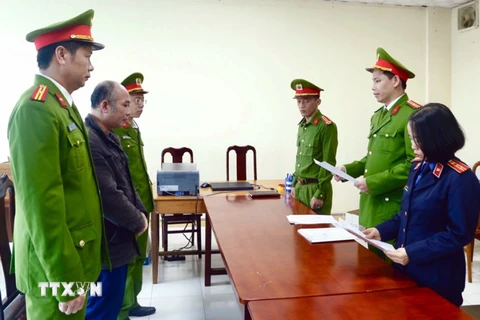 Lực lượng chức năng đọc lệnh khởi tố và bắt tạm giam Trần Quang Anh. (Ảnh: TTXVN phát)