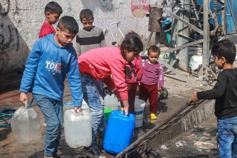 Trẻ em lấy nước tại vòi nước công cộng ở thành phố Rafah, Dải Gaza. (Ảnh: AFP/TTXVN)