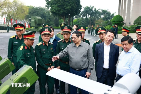 Thủ tướng Phạm Minh Chính trao đổi về sản phẩm công nghệ cao của Tập đoàn Viettel. (Ảnh: Dương Giang/TTXVN)