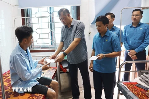 Ông Nguyễn Minh Dũng trao hỗ trợ các công nhân bị tai nạn. (Ảnh: Công Tường/TTXVN)