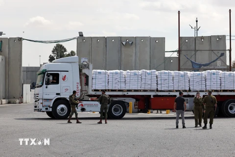 Lực lượng an ninh Israel kiểm tra xe chở hàng nhân đạo vào Dải Gaza qua cửa khẩu Kerem Shalom. (Ảnh: AFP/TTXVN)