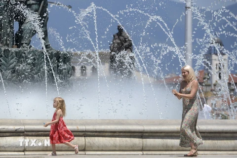 Người dân tránh nóng bên vòi phun nước tại Skopje, Bắc Macedonia. (Ảnh: AFP/TTXVN)