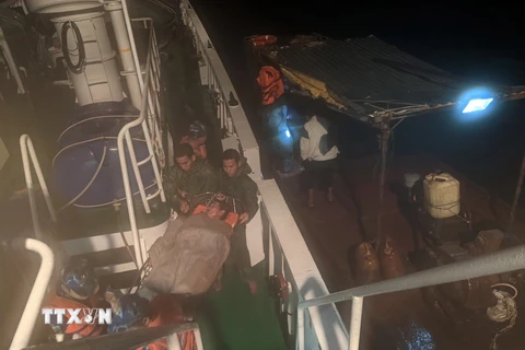 Chuyển bệnh nhân Nguyễn Văn Nhân từ tàu ngư dân lên tàu 468 (bên trái) để đưa về đảo Trường Sa điều trị bệnh. (Ảnh: TTXVN phát)