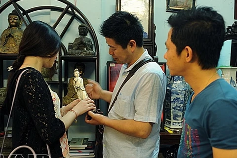 Một du khách người Trung Quốc tìm thấy bức tượng Phật Bà Quan Âm có niên đại từ thời nhà Thanh tại một cửa hàng bán đồ cổ ở phố Lê Công Kiều. (Ảnh: Đặng Kim Phương/Báo ảnh Việt Nam)