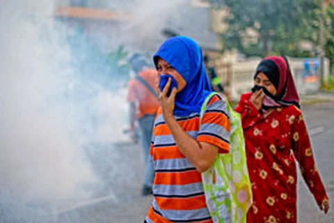 Người dân Malaysia che mũi khi đi qua khu vực xịt thuốc trừ sâu trong chiến dịch phòng chống sốt xuất huyết ở Ampang, ngoại ô Kuala Lumpur ngày 11/2 vừa qua. (Nguồn: AFP)