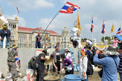 Người biểu tình trộn bêtông để dựng bức tường trước lối vào Tòa nhà Chính phủ ở Bangkok ngày 17/2 vừa qua. (Ảnh: AFP/TTXVN)