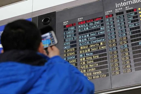 Một người chụp lại bảng thông báo chuyến bay ở sân bay Bắc Kinh, trong đó dòng màu đỏ trên cùng là thông tin về chuyến bay gặp sự cố. (Nguồn: Reuters)