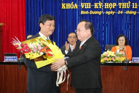 Chủ tịch Ủy ban Nhân dân tỉnh Lê Thanh Cung (bên phải) chúc mừng ông Võ Văn Minh. (Ảnh: Quách Lắm/ TTXVN)