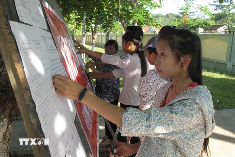 Các thí sinh xem thông báo và hướng dẫn kỳ thi tốt nghiệp Trung học phổ thông. (Ảnh: Nguyễn Văn Nhật/TTXVN)