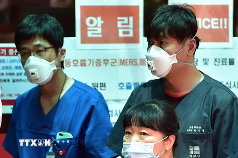 Nhân viên y tế Hàn Quốc bên các tấm biển cảnh báo về MERS tại trung tâm y tế quốc gia. (Ảnh: AFP/TTXVN)