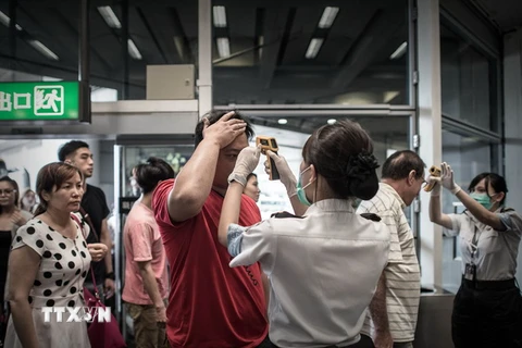 Nhân viên sân bay quốc tế Hong Kong (Trung Quốc) kiểm tra thân nhiệt của hành khách để ngăn ngừa khả năng lây lan dịch MERS ngày 5/6 vừa qua. (Ảnh: AFP/TTXVN)