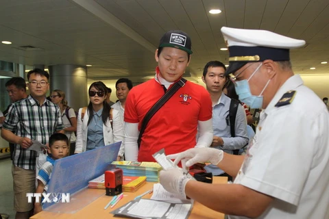 Khách đến từ những nước có dịch MERS-CoV được kiểm tra khu kiểm dịch sân bay Tân Sơn Nhất. (Ảnh: Phương Vy/TTXVN)