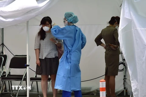 Nhân viên y tế kiểm tra thân nhiệt hành khách tại Bệnh viện Trường đại học Konkuk ở Seoul ngày 24/6. (Ảnh: AFP/TTXVN)