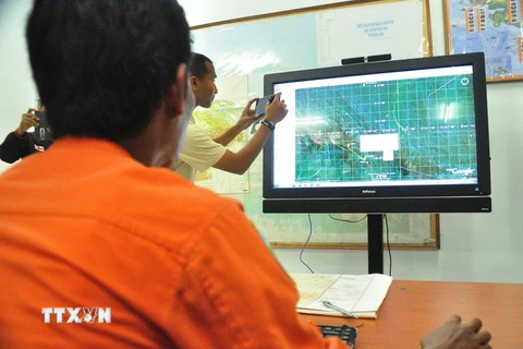 Nhân viên Cơ quan tìm kiếm và cứu nạn quốc gia Indonesia theo dõi địa hình khu vực ở Jayapura trên bản đồ nhằm tìm kiếm máy bay mất tích. (Ảnh: AFP/TTXVN)