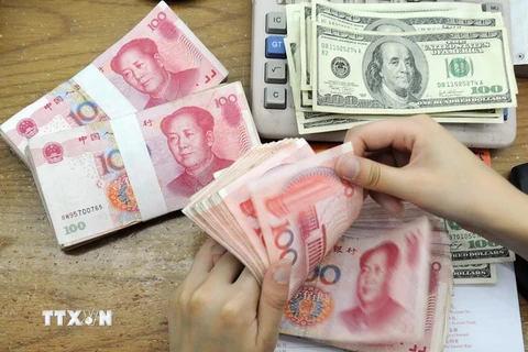 Kiểm tiền nhân dân tệ và USD tại ngân hàng ở tỉnh An Huy, Trung Quốc. (Ảnh: AFP/TTXVN)