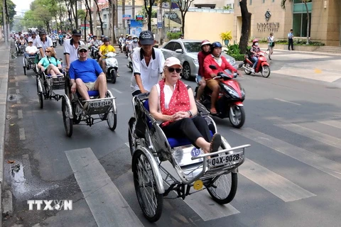 Khách du lịch quốc tế tham quan Thành phố Hồ Chí Minh bằng phương tiện xích lô. (Ảnh: An Hiếu/TTXVN)