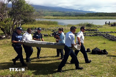 Chuyển mảnh vỡ máy bay được nghi là của MH370 trên đảo Reunion ngày 29/7 vừa qua. (Ảnh: AFP/TTXVN)