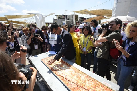 Nhân viên của Sách kỷ lục Guinness đo chiều dài chiếc bánh pizza tại Hội chợ triển lãm EXPO ở Milan. (Ảnh: AFP/TTXVN)