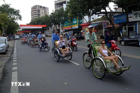 Khách du lịch quốc tế tham quan thành phố Huế trên phương tiện xích lô. (Ảnh: Quốc Việt/TTXVN)