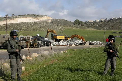 Cảnh sát biên giới Israel đứng canh trong khi phá dỡ một ngôi nhà của người Palestine ở thị trấn West Bank ngày 20/1. (Ảnh: Reuters)