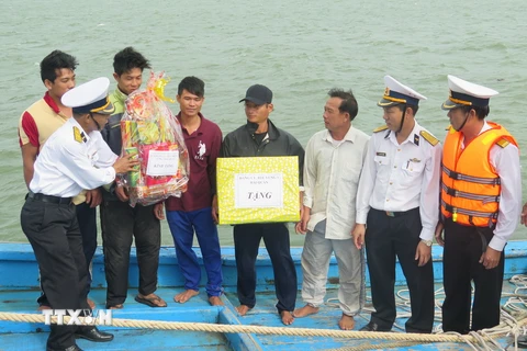 Cán bộ Vùng 3 Hải quân Đà Nẵng trao quà cho các thuyền viên vào bờ an toàn. (Ảnh Viết Ý/TTXVN)
