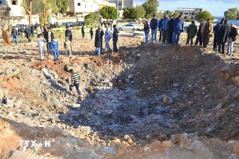 Người dân Libya vây quanh một hố bom sau cuộc không kích các mục tiêu IS tại Derna, cách thủ đô Tripoli, Libya khoảng 100km ngày 7/2 vừa qua. (Ảnh: AFP/TTXVN)