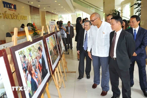 Lãnh đạo Thông tấn xã Việt Nam, Đại sứ Cu Ba tại Việt Nam Herminio Lopez Diaz và cán bộ nhân viên Đại sứ quán xem khu trưng bày ảnh với chủ đề "Việt Nam-Cuba, 55 năm Đoàn kết và Hợp tác." (Ảnh: Minh Đức/TTXVN)