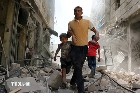 Người dân Syria sơ tán khỏi khu vực đổ nát sau một cuộc không kích ở Aleppo ngày 22/4 vừa qua. (Ảnh: AFP/TTXVN)