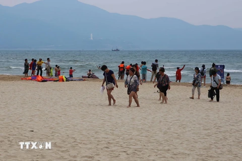 Khách du lịch và người dân đi dạo chơi, tắm biển trên các bãi biển. (Ảnh: Trần Lê Lâm/TTXVN) 