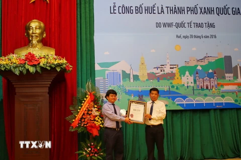 Đại diện lãnh đạo thành phố Huế (trái) đón nhận danh hiệu "Thành phố xanh quốc gia 2016" do WWF trao tặng. (Ảnh: Hồ Cầu/TTXVN)