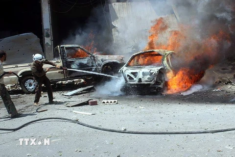 Lực lượng dân phòng Syria dập lửa trên chiếc xe ôtô bốc cháy sau một cuộc không kích tại Idlib, miền bắc Syria ngày 13/8. (Ảnh: EPA/TTXVN)