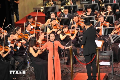 Ca sỹ Lan Anh cùng Dàn nhạc giao hưởng Việt Nam biểu diễn ca khúc "Tiếng hát giữa rừng Pắc Bó," tại buổi hòa nhạc quốc gia "Điều Còn Mãi 2015." (Ảnh: Minh Đức/TTXVN)