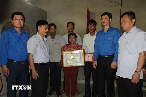 Trao huy hiệu "Tuổi trẻ dũng cảm" tặng em Trần Thị Thu Hà cho đại diện gia đình. (Ảnh: Khiếu Tư/TTXVN)