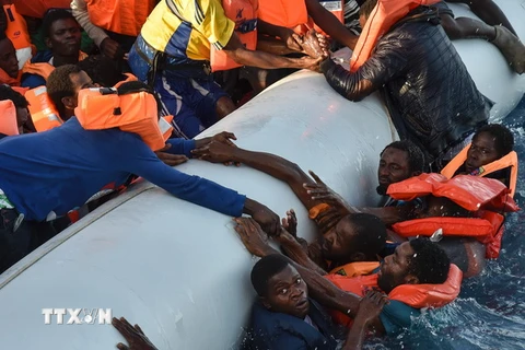 Người di cư rơi xuống nước trong sự cố lật thuyền ngoài khơi Libya ngày 3/11. (Ảnh: AFP/TTXVN)