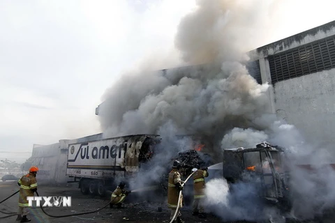Nhân viên cứu hỏa dập lửa sau khi xe buýt bị đốt phá tại Rio de Janeiro, ngày 2/5. (Ảnh: EPA/TTXVN)