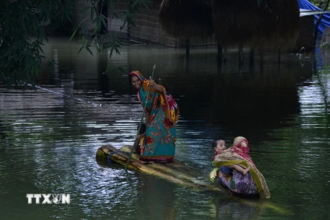 Người dân Ấn Độ di chuyển tại khu vực ngập lụt ở Assam bằng bè tự chế ngày 10/7 vừa qua. (Ảnh: EPA/TTXVN)