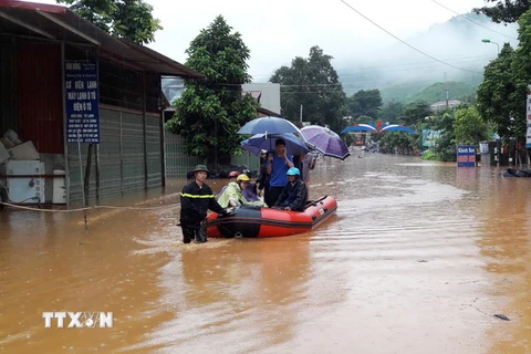 Lực lượng chức năng dùng xuồng đưa người dân vượt qua đoạn ngập sâu tại thị trấn Ít Ong, huyện Mường La. (Ảnh: Nguyễn Cường/TTXVN)