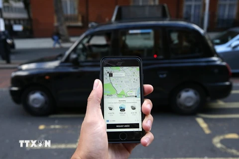 Một khách hàng dùng điện thoại di động để gọi dịch vụ xe của Uber tại London. (Ảnh: AFP/TTXVN )