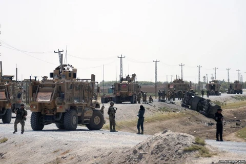 Những người lính NATO theo dõi đống đổ nát của xe tại nơi xảy ra cuộc tấn công ở Kandahar ngày 15/9 vừa qua. (Nguồn: AFP)