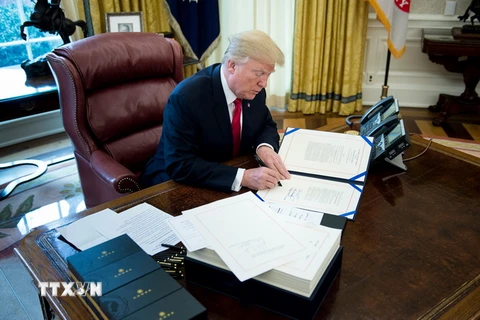 Tổng thống Mỹ Donald Trump ký một văn bản ở Washington DC., ngày 22/12/2017. (Ảnh: AFP/TTXVN)