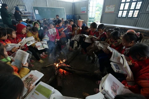 Học sinh nội trú trường Tiểu học Tỏa Tình, huyện Tuần Giáo ngồi ôn bài bên đống lửa sưởi ấm trong những ngày giá rét. (Ảnh: Phan Tuấn Anh/TTXVN)