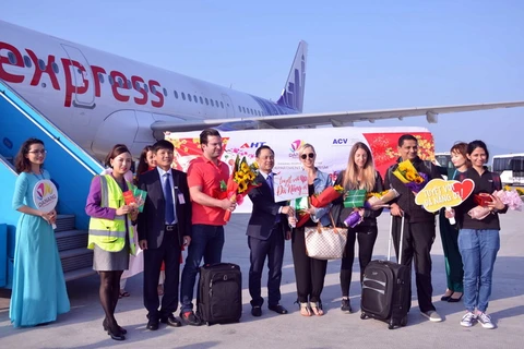 Tặng hoa chúc mừng những vị khách quốc tế đầu tiên đến "xông đất" Đà Nẵng bằng đường hàng không. (Ảnh: TTXVN phát)
