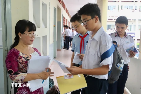Giám thị coi thi đọc tên và số báo danh thí sinh tại địa điểm thi trường THPT Bùi Thị Xuân, quận 1. (Ảnh: Quang Nhựt/TTXVN)
