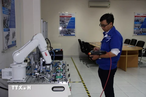 Các kỹ sư điều chỉnh hoạt động của robot tại phòng thực hành robot tự động hóa Trung tâm đào tạo và chuyển giao công nghệ Việt-Nhật. (Ảnh: Tiến Lực/TTXVN) 